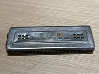 Top view of the antique M. Hohner Echo harmonica showing the engraved word 'ECHO', decorative engraving, and metal air holes.