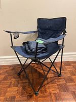 Side angle photo showing the chair's blue fabric seat and backrest, metal frame, and armrests with cup holder on right side.