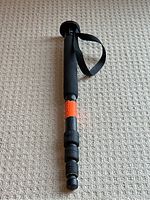 Full length view of the black carbon fibre monopod with foam grip and wrist strap, collapsed.