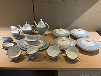 View of entire Royal Doulton Reflection dinnerware set on a table, showing teapots, creamers, cups, plates, and covered serving dishes.