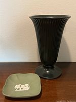 Black fluted Wedgwood vase with pedestal base beside green ashtray