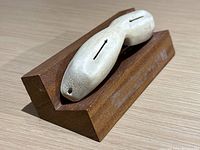 Angled view of carved snow goggles resting on wooden stand
