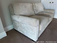 Side-front angle showing rolled arm and profile of beige sofa bed