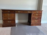 Full frontal view of mahogany desk showing all drawers and brass handles
