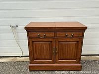 Front view of the vintage console table with closed top and cabinets, showing the wood finish and brass handles.