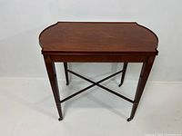 Full front view showing the tabletop shape, legs, cross stretcher, and casters.