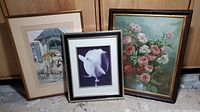 Three framed art prints grouped together showing a woman with umbrella, close-up white flower, and pink rose bouquet.