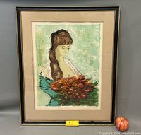 Framed lithograph artwork showing a young woman holding flowers, with beige mat and black frame.