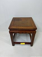 Front angled view of the carved small wooden end table showing the legs, apron, and top surface with some discoloration.
