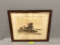 Full view of framed engraving showing riverside cabin scene, distressed matting, and frame design