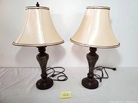 Pair of marbleized metal base table lamps with cream bell-shaped lampshades; one lamp has a finial on top, the other does not.