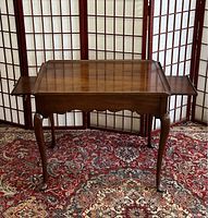 Front view of wooden Queen Anne style tea table with slide out tray extended on both sides