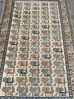 Close-up photo of the rug showing tribal geometric motifs in soft earth colors with repeated patterns.