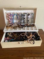 Jewellery box open showing hanging beaded necklaces and compartment tray
