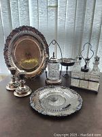 Full lot displaying all seven items on a flat surface, showing trays, candlesticks, pickle castor, tazza, and cruet set, providing overall condition and arrangement.