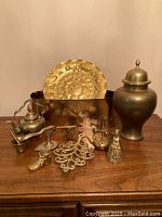Lot of vintage solid brass items on wooden table, showing all pieces together including urn, tray, holders and figurines
