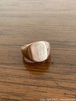 Front view of oval signet face with faded monogram engraving on wooden surface