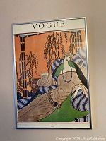 Front view of vintage Vogue poster in chrome frame, showing full artwork of reclining woman and 'VOGUE' title at top.