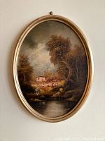 Full view of the framed oval oil painting depicting the landscape with trees, water, house, and figure.