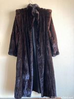 Full-length front view of brown mink coat hanging against wall