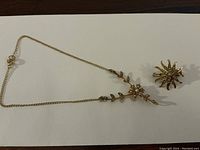 Overhead view of both bracelet and brooch on white background.