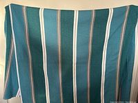 Full view of the teal striped woven blanket showing its colors and size.