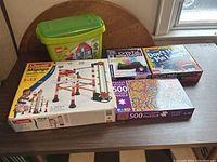Kids toys and games lot on table including LEGO, marble run, puzzles, nightlight kit and a card game
