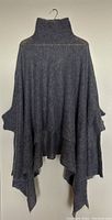 Front view of the grey wool knit poncho showing the turtleneck and asymmetrical draped hemline.