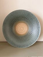 Top view showing textured turquoise-blue interior and spiral center of ceramic bowl.