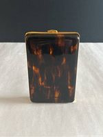 Front view of the glossy faux tortoiseshell cigarette case showing amber and brown mottled pattern.