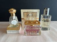 Lot of three women's luxury perfume bottles displayed together on a white surface with dark background.
