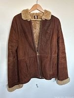Front view of women's brown shearling coat on hanger showing zipper and shearling collar and cuffs.