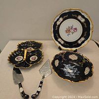 Overview of divided serving dish, serving utensils, and cobalt plate with floral center and gilded edge