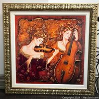 Frontal view of the framed art print depicting two women playing violin and cello, within an ornate gold frame