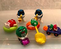Six vintage M&M toy figures shown together on display with various colorful poses and accessories.
