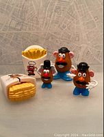Photo showing three Mini Mr. Potato Head figurines and two Burger King French fry toy packs with logos and character designs