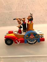 Side view of the vintage Popeye toy car showing Popeye with telescope and Olive Oyl seated in the boat section of the car, along with Bluto standing behind.