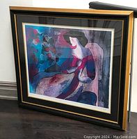 Full view of the framed seriolithograph showing the vibrant colorful figure and floral elements in a gilt frame with matting.