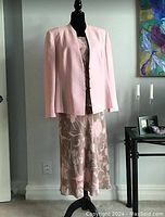 Full view of the Jacques Vert 3-piece outfit on a dress form showing the pink jacket over the floral patterned top and skirt.