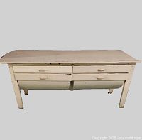 Front view of antique wooden kitchen work table showing 4 drawers including 2 belly-shaped flour bins, painted in off-white with wear.