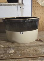 Full view of the large stoneware crock with a dark brown upper glaze and beige lower glaze, size 6 marked on front.