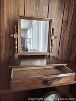 Full view of antique style wooden swivel mirror on a flat base with a single drawer pulled open showing interior space.