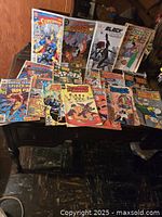 Image showing a spread of comic books featuring Superman, Flash, Black Widow, Spider-Man, and Road Runner titles arranged on a table.
