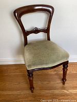 Front view of antique balloon back dining chair showing carved rosewood frame and pale green velvet seat upholstery.