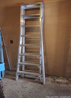 Full view of the aluminum ladder showing the extended width and seven wide steps with rubber feet on the bottom for stability.