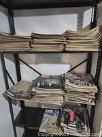 Stacks of multiple vintage LIFE magazines on a black metal shelving unit.