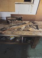 Wooden tool carrier on workbench with various tools including saw, wrench, pry bars and hammers
