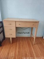 Full view of blonde wood sewing cabinet with drop-in machine lid closed