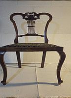 Front view of the vintage mahogany side chair showing curved legs and upholstered seat.