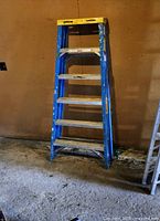 Full view of the Werner aluminum A-frame ladder showing blue sides and yellow top.